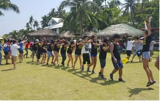 A blindfolded team moving together in a line during an outdoor team building game